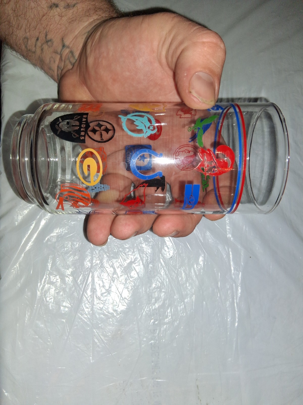 This 16 oz drinking tumbler features throwback logos for various NFL teams,