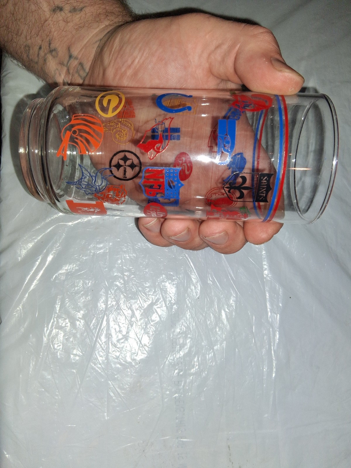 This 16 oz drinking tumbler features throwback logos for various NFL teams,