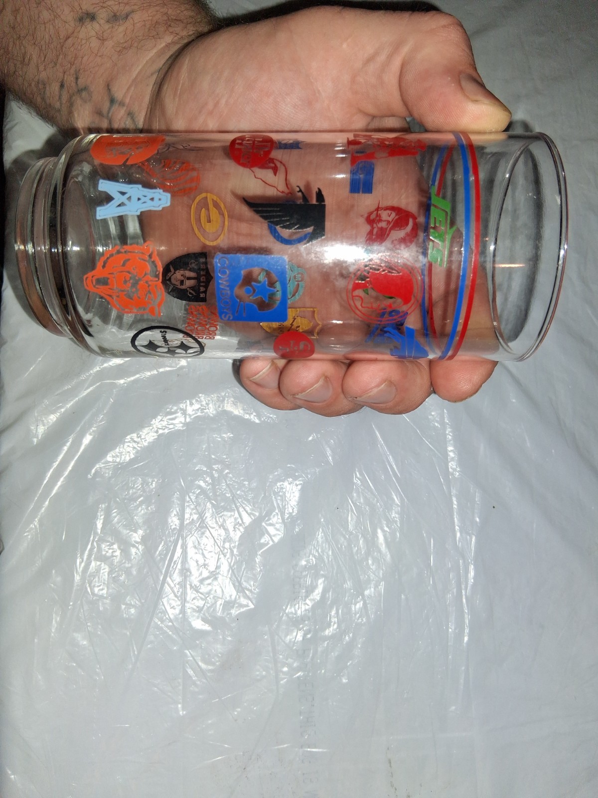 This 16 oz drinking tumbler features throwback logos for various NFL teams,