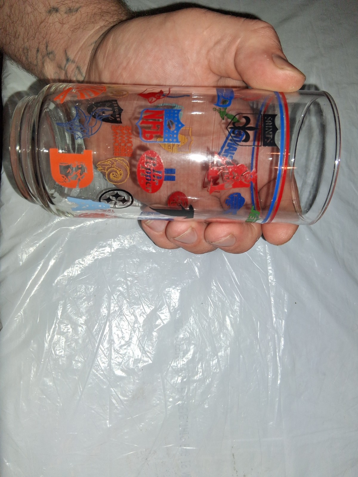 This 16 oz drinking tumbler features throwback logos for various NFL teams,